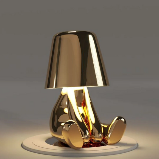 Gold metallic figurine table lamp with conical shade and rounded base, LED light glow