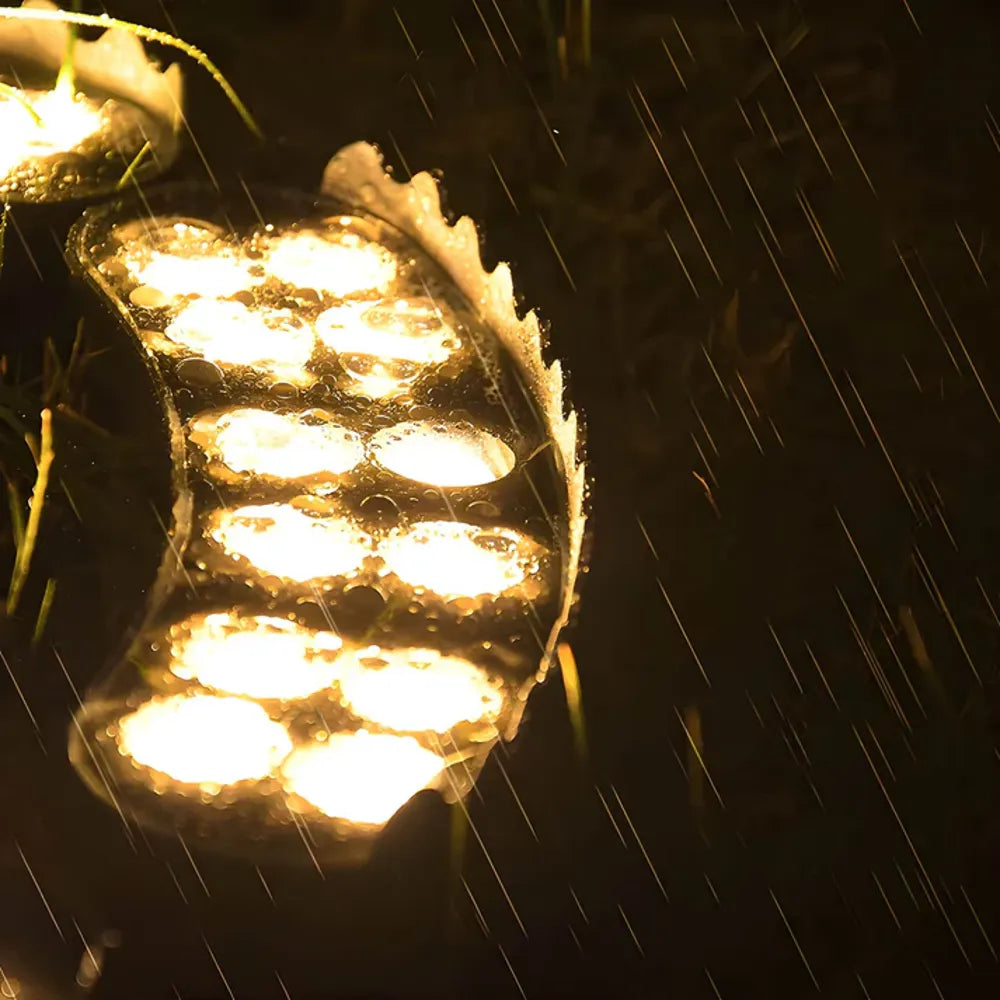 Solar LED garden spotlight shining warm LEDs through rain on a tree trunk