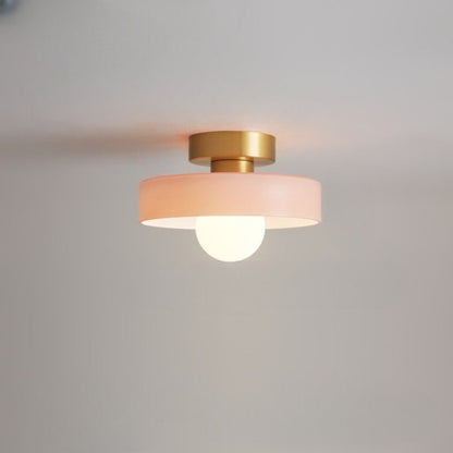 Ceiling light with round peach glass shade and gold metal top, glowing bulb