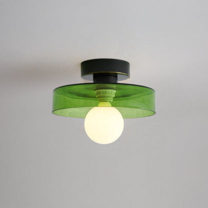 Ceiling light with round green glass shade and dark metal top, glowing bulb