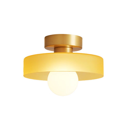 Ceiling light with round amber glass shade and gold metal top, glowing bulb