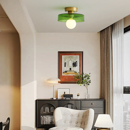 Round ceiling light with gold metal base and green glass shade over white bulb.