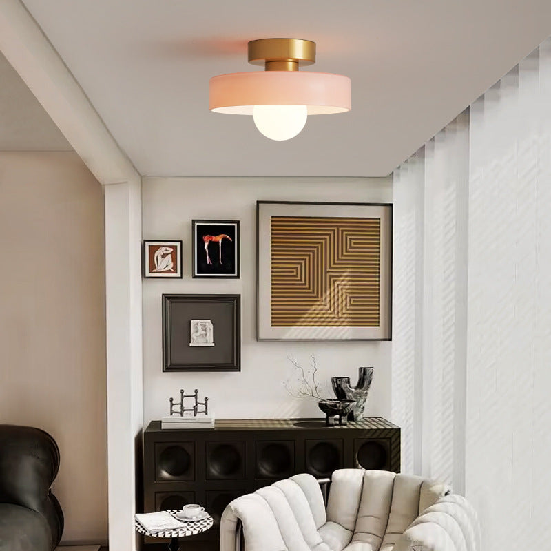 Round ceiling light with gold metal base and pale pink glass shade.