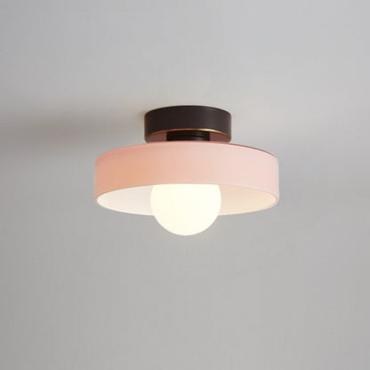 Ceiling light with round pink glass shade and dark metal top, glowing bulb visible