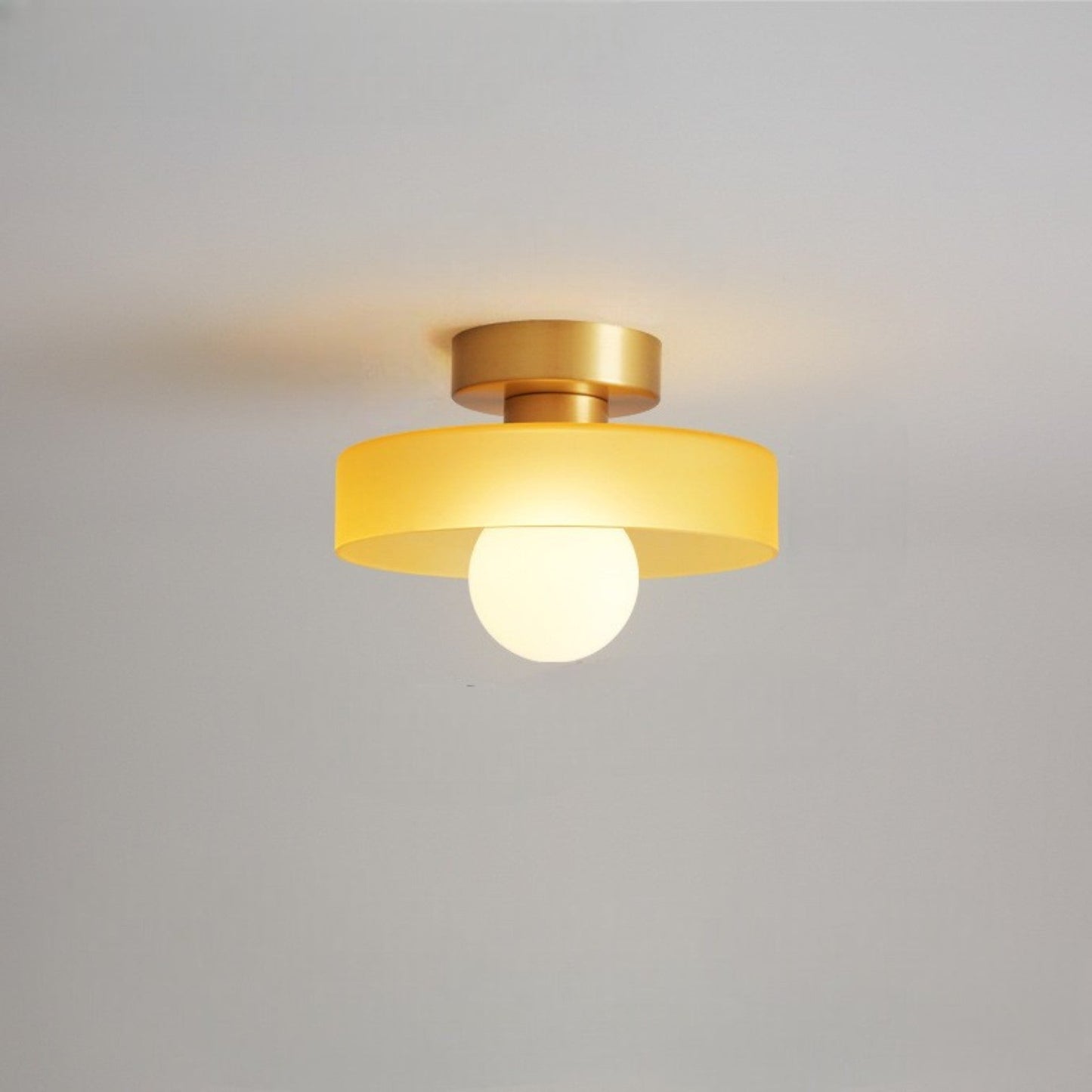 Ceiling light with round amber glass shade and gold metal top, centered bulb glow