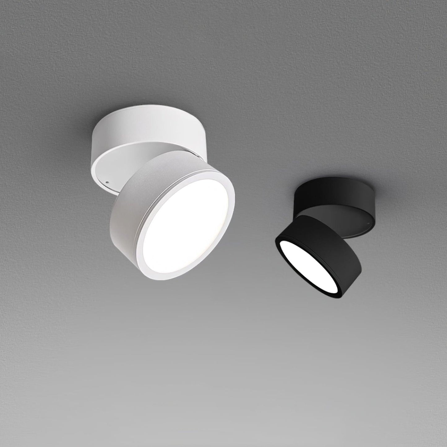 White and black LED ceiling spotlights side-by-side with warm illuminated lenses.