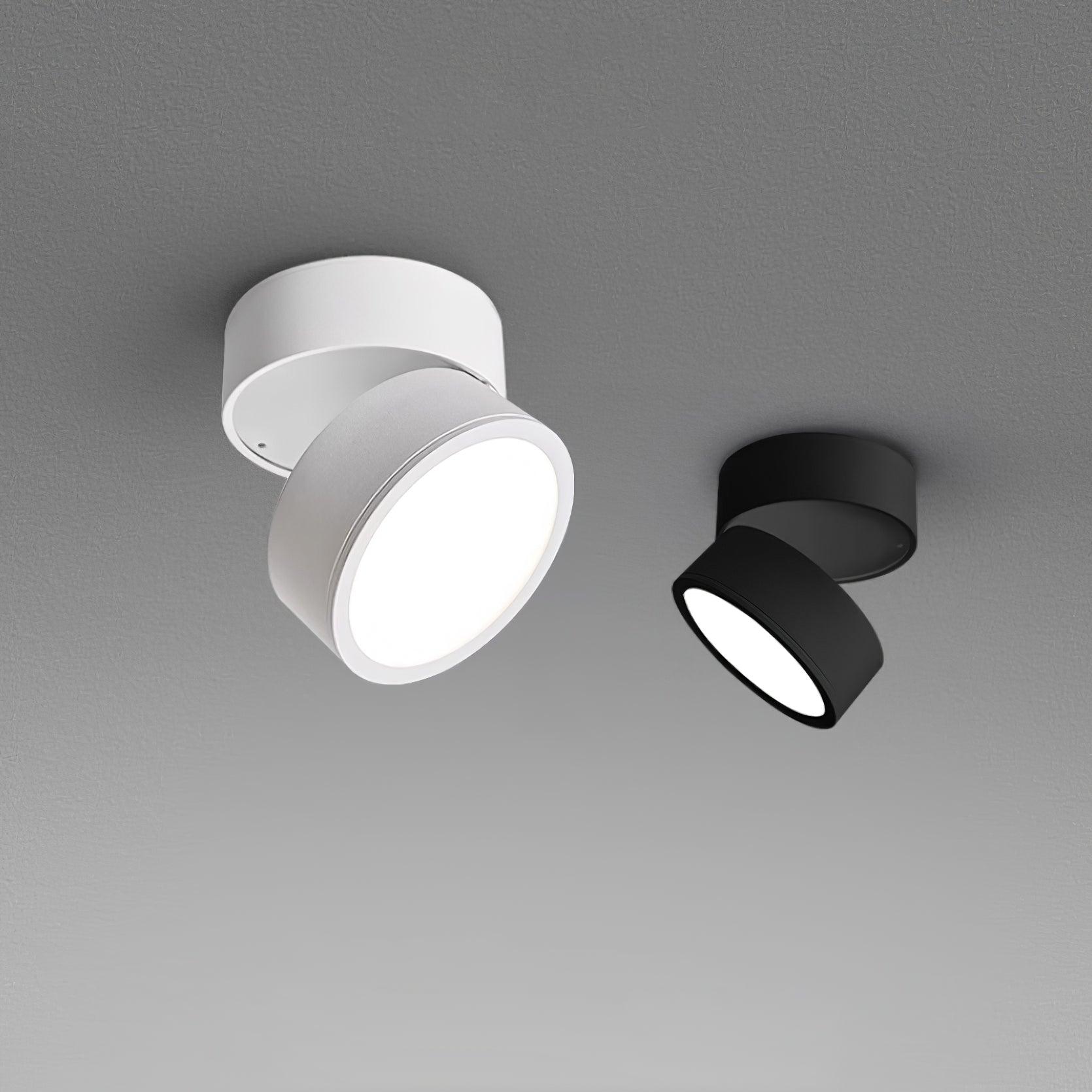White and black LED ceiling spotlights side-by-side with warm illuminated lenses.