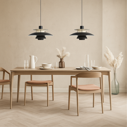 Two black pendant lights with layered dome shades over dining table