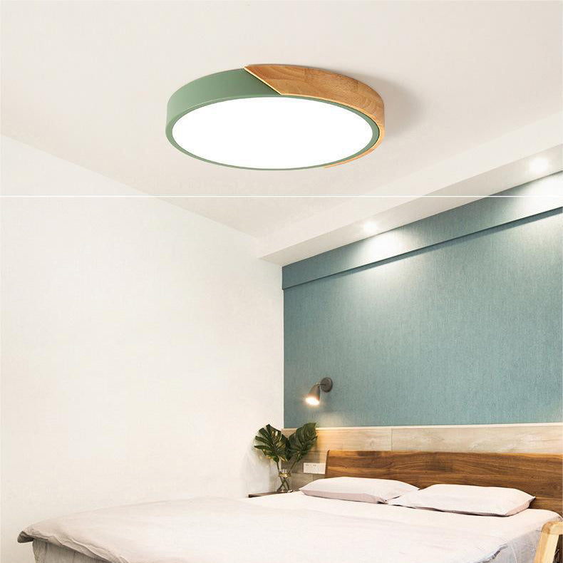 Round ceiling light with white acrylic diffuser and green metal rim, warm wood accent