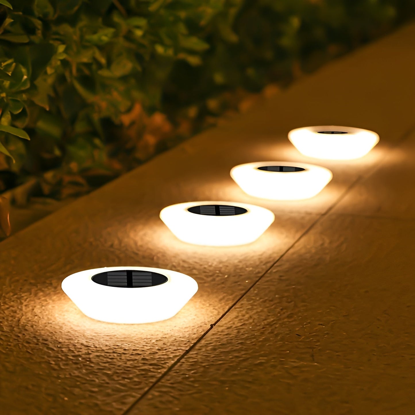 Set of round solar ground lights with glowing white tops and black solar panels