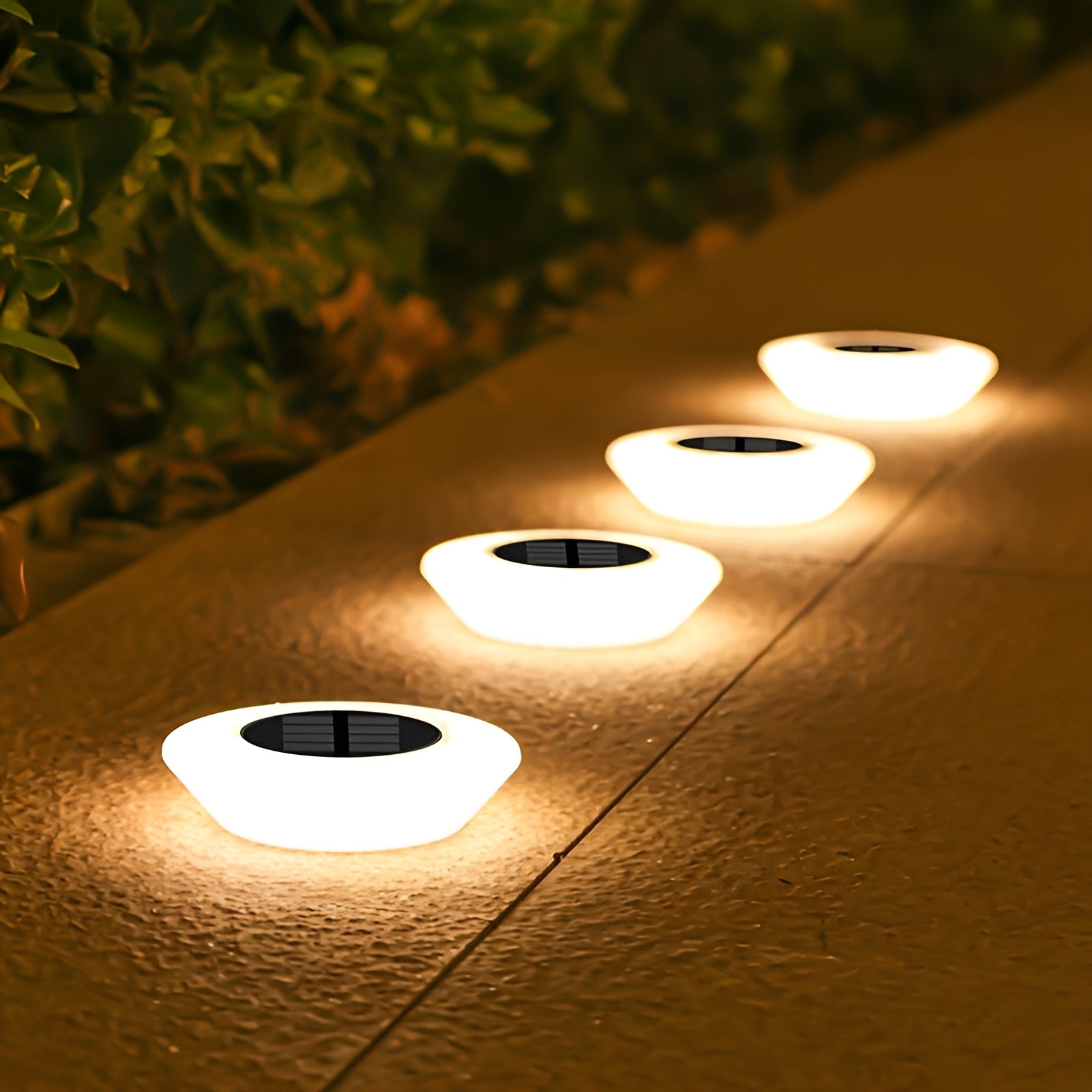 Set of round solar ground lights with glowing white tops and black solar panels