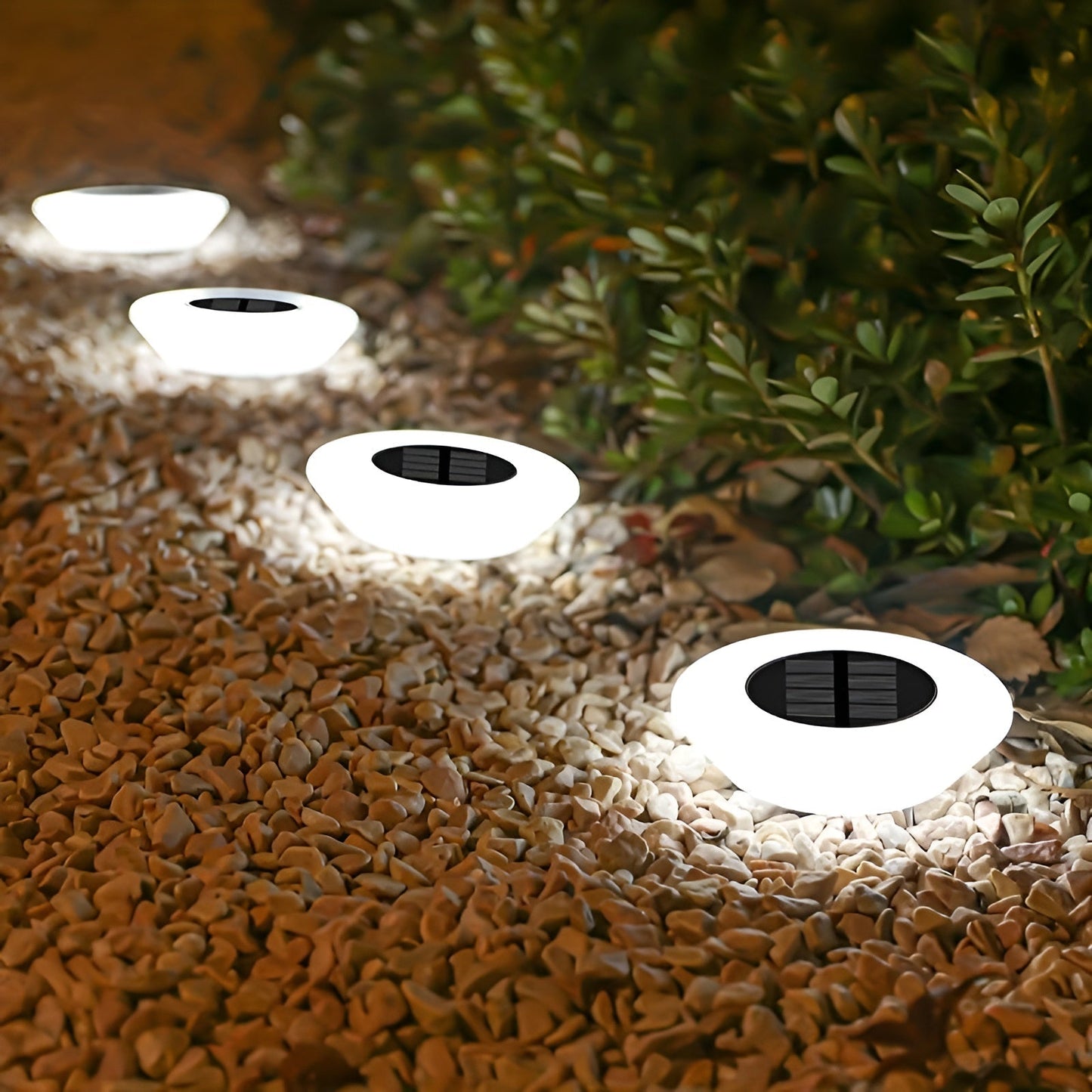 Multiple round solar garden ground lights on gravel, white housings with black panels