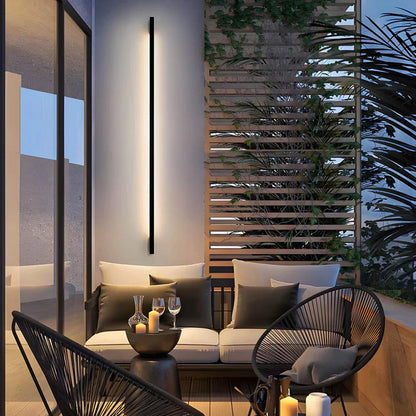 Outdoor wall-mounted LED light strip with slim dark housing, emitting a white linear glow