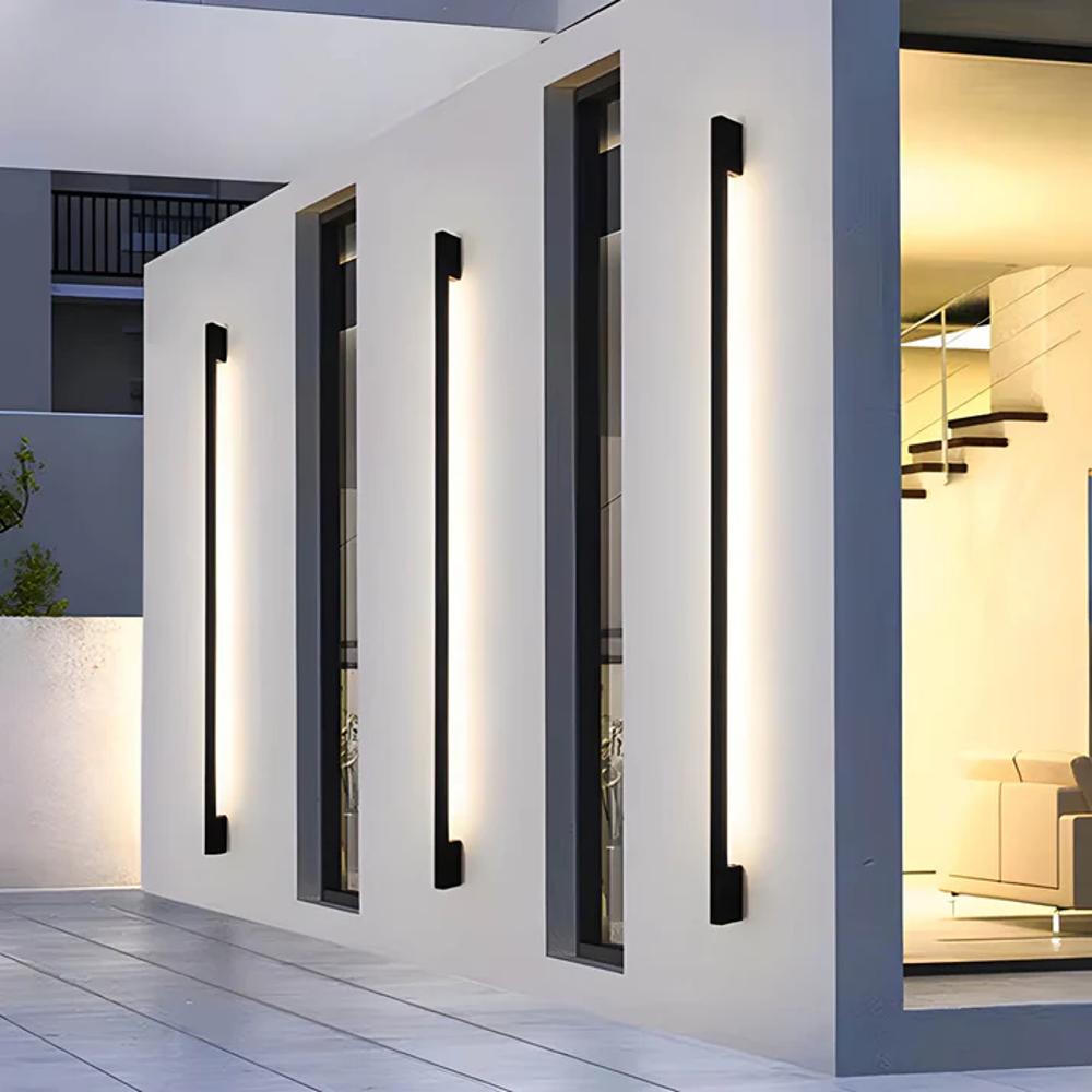 Facade-mounted LED wall light strips with slim dark housings, casting a white linear glow