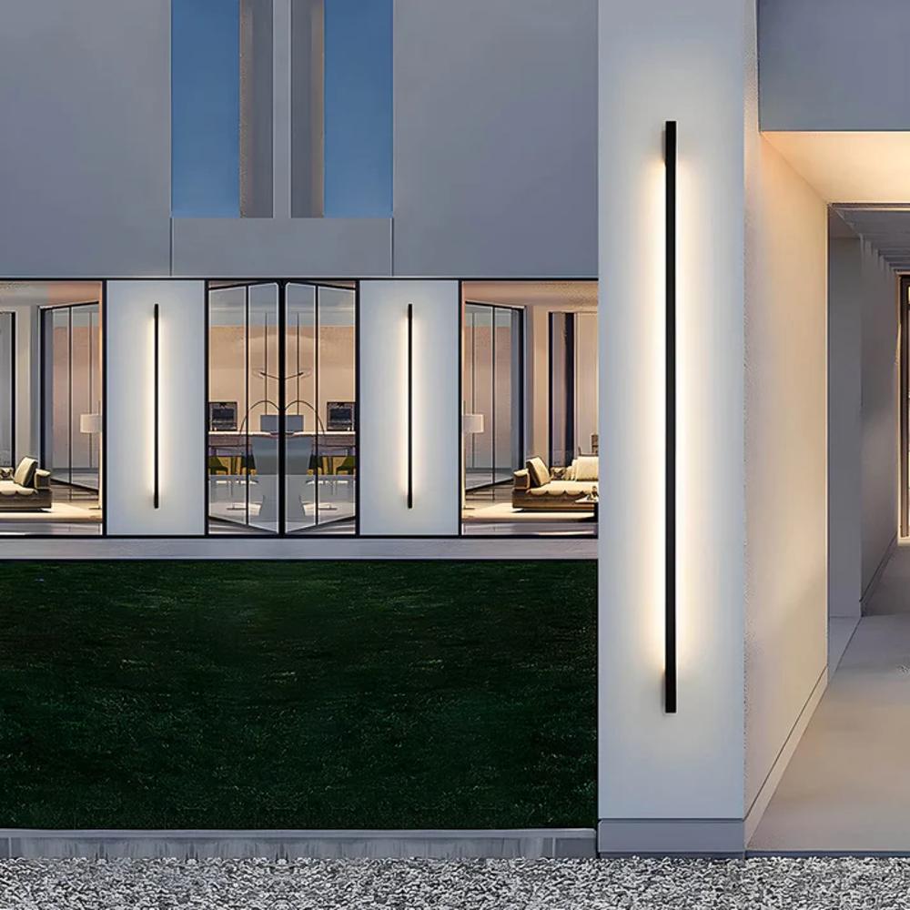 Corner outdoor LED wall light strip with slim dark housing, emitting a white linear glow