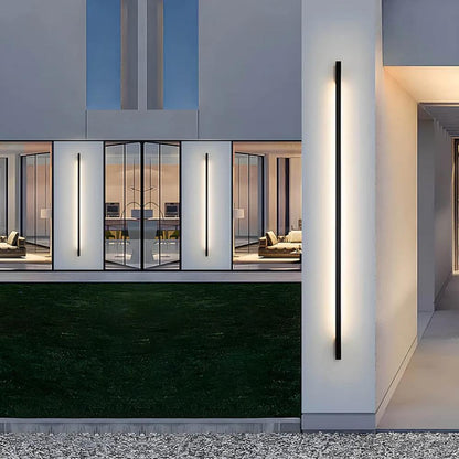Corner outdoor LED wall light strip with slim dark housing, emitting a white linear glow