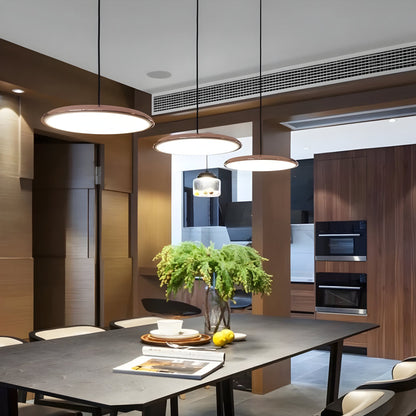 Rose gold metal pendant light with circular ring and glass shade, hanging over dining table