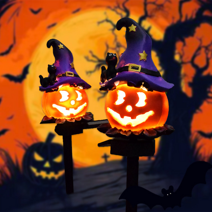 Two glowing pumpkin solar lights shaped like witch hats with bats and star accents