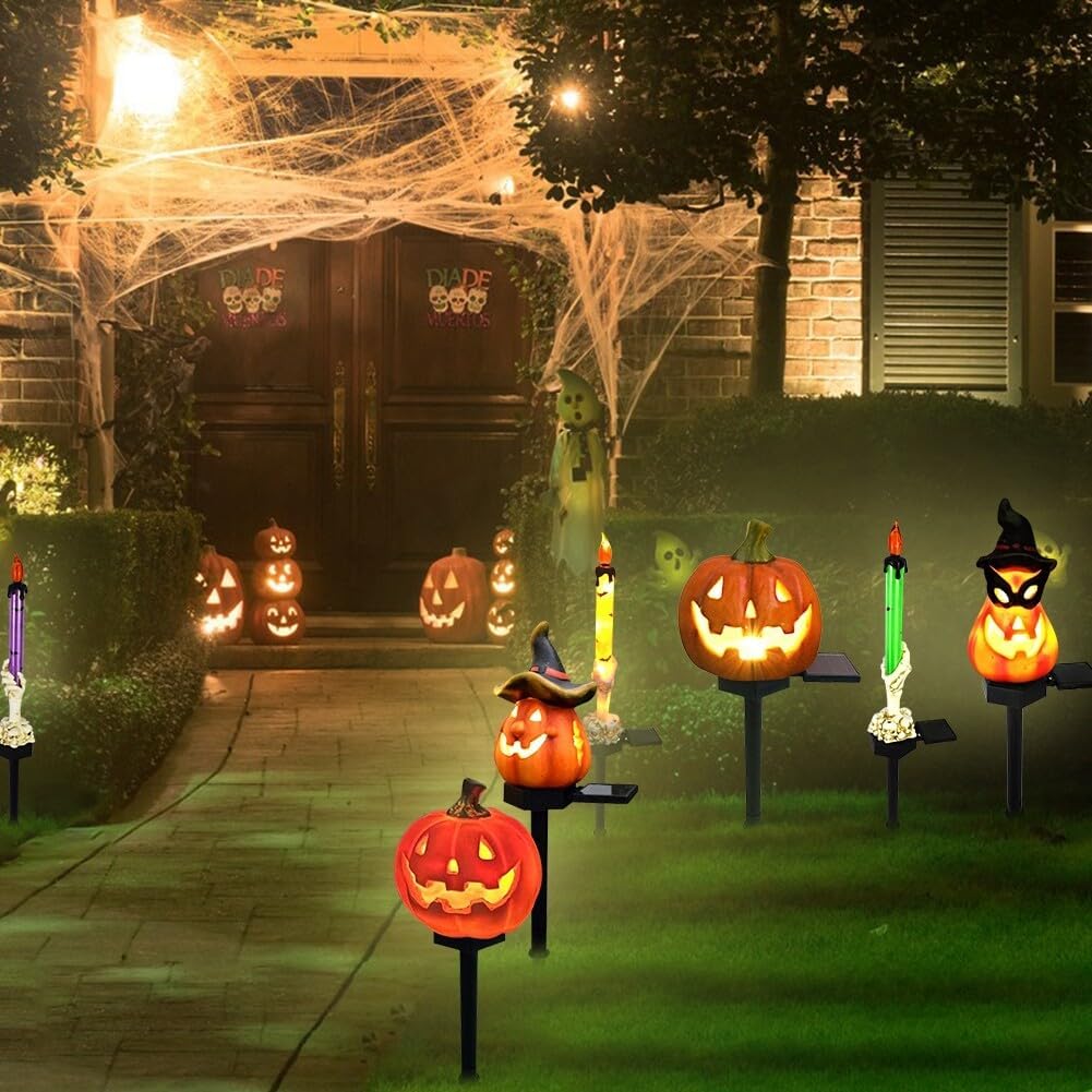 Glowing Halloween pumpkin solar garden lights on black stakes along a walkway at night
