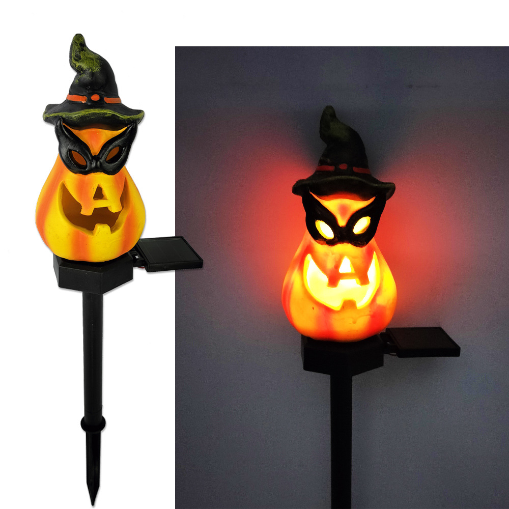 Glowing cat-faced witch hat solar garden light on black stake, orange light around