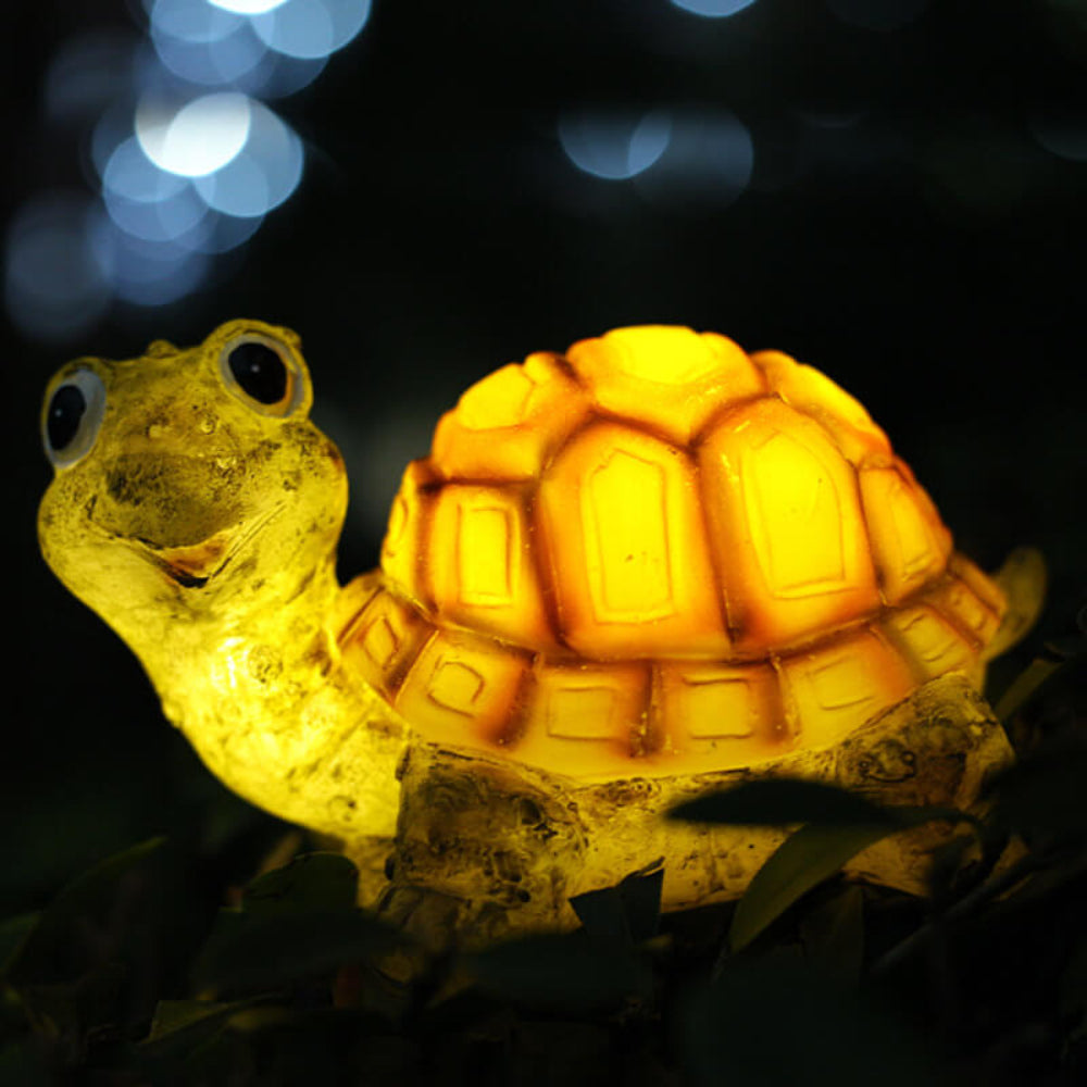 Solar turtle garden light figure in orange resin, glowing LED over leaves