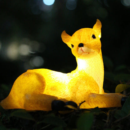 Solar deer garden light figure in warm yellow resin, sitting on leaves under LED light