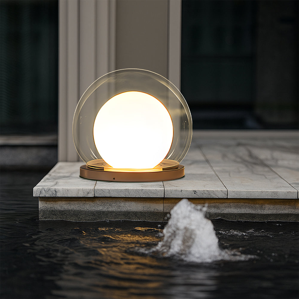 Outdoor LED ball garden lamp with clear globe and warm light on stone platform near water