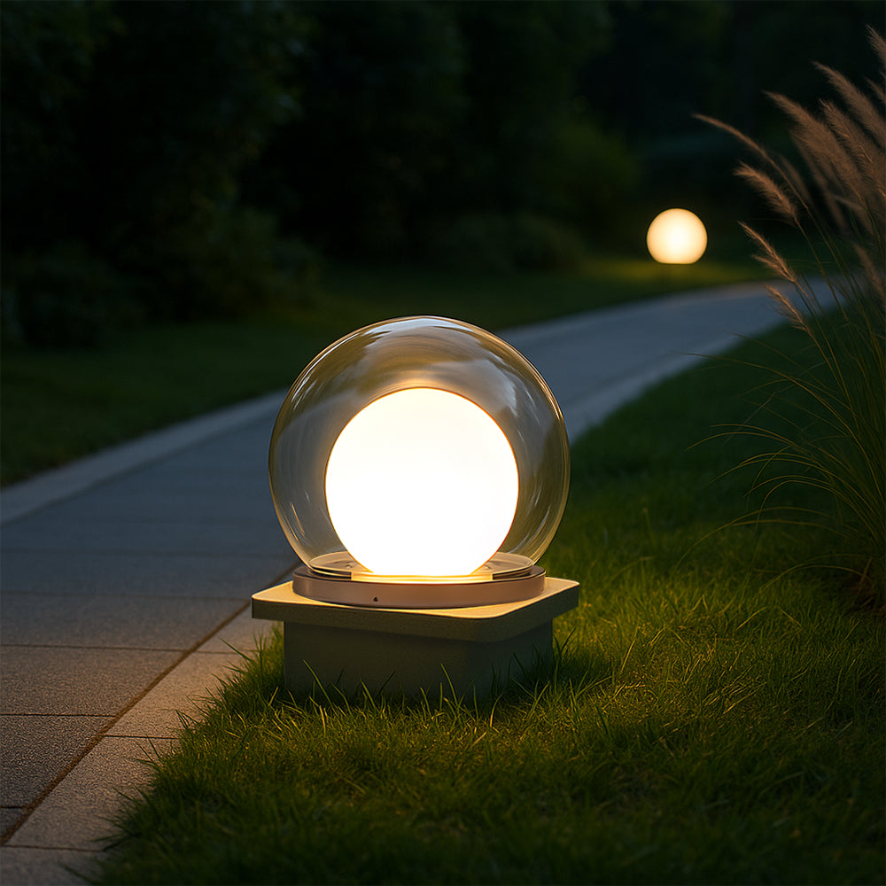Outdoor LED ball garden lamp with clear globe, warm light, and dark base on walkway