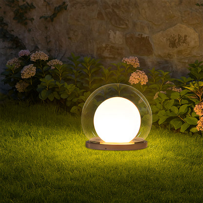 Outdoor LED ball garden lamp with clear globe and warm glow on dark base in grass